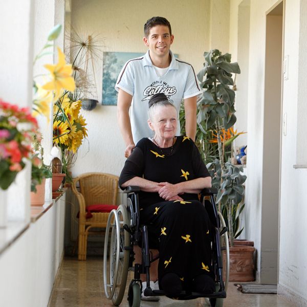 Pfleger schiebt Seniorin im Rollstuhl